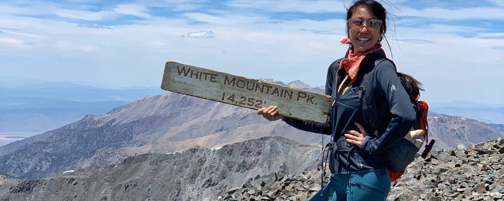 girl and white mountain summit sign 14252