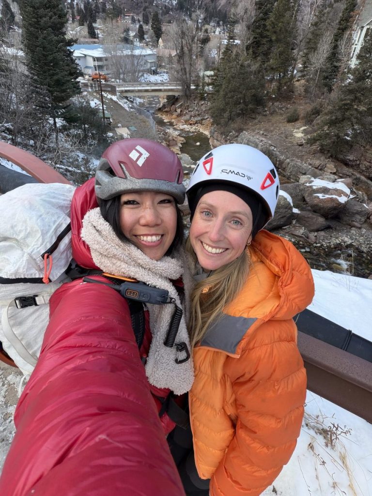 Two smiling women wearing climbing helmets at Ouray Ice Park in 2026