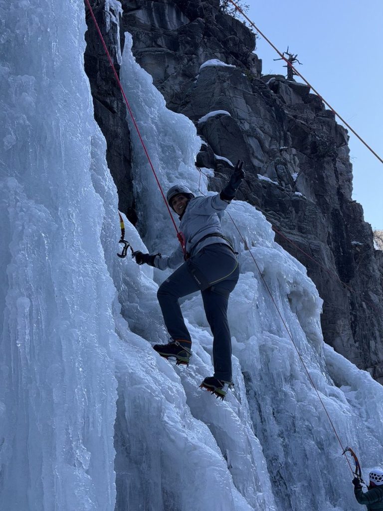 Participant climbing a frozen waterfall during the women’s retreat in Ouray
